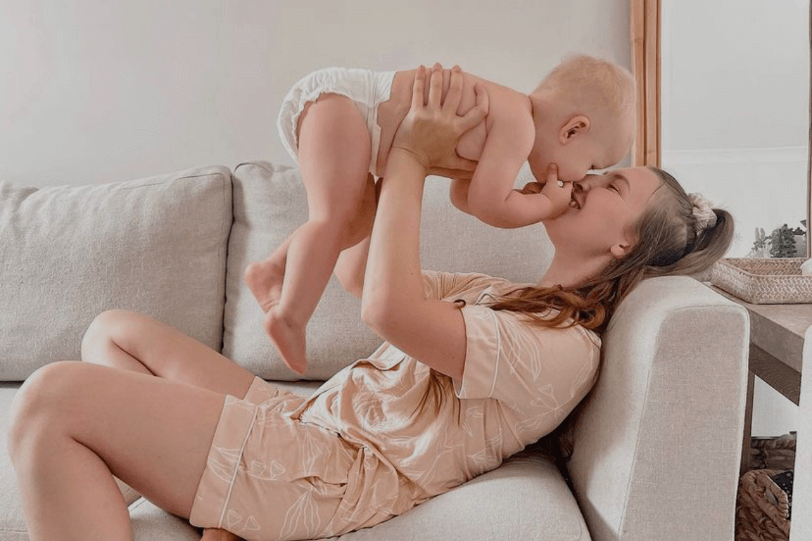 Happy mum and baby smiling together on the sofa, enjoying a calm moment with Cuddlies eco nappies in use