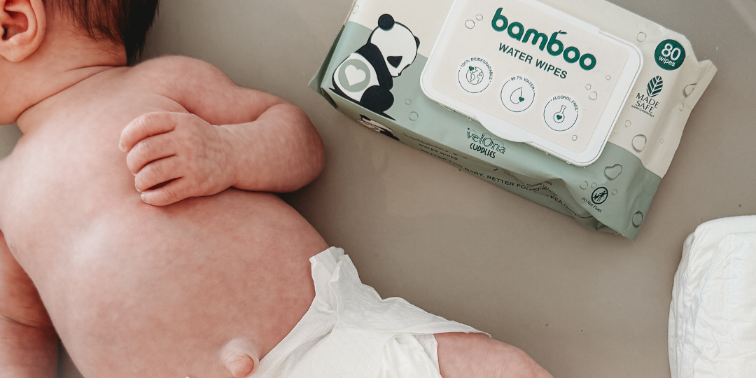 Newborn baby lying on a soft surface wearing a nappy, with a pack of baby water wipes placed beside them - ideal for illustrating gentle, safe options for newborn skincare.