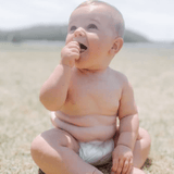 Happy baby wearing Cuddlies bamboo eco nappy at the beach - nappies that are breathable, leak-proof and perfect for summer adventures