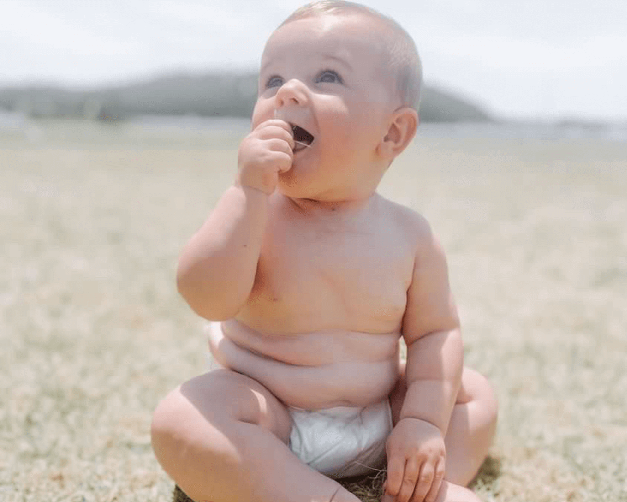 Happy baby wearing Cuddlies bamboo eco nappy at the beach - nappies that are breathable, leak-proof and perfect for summer adventures