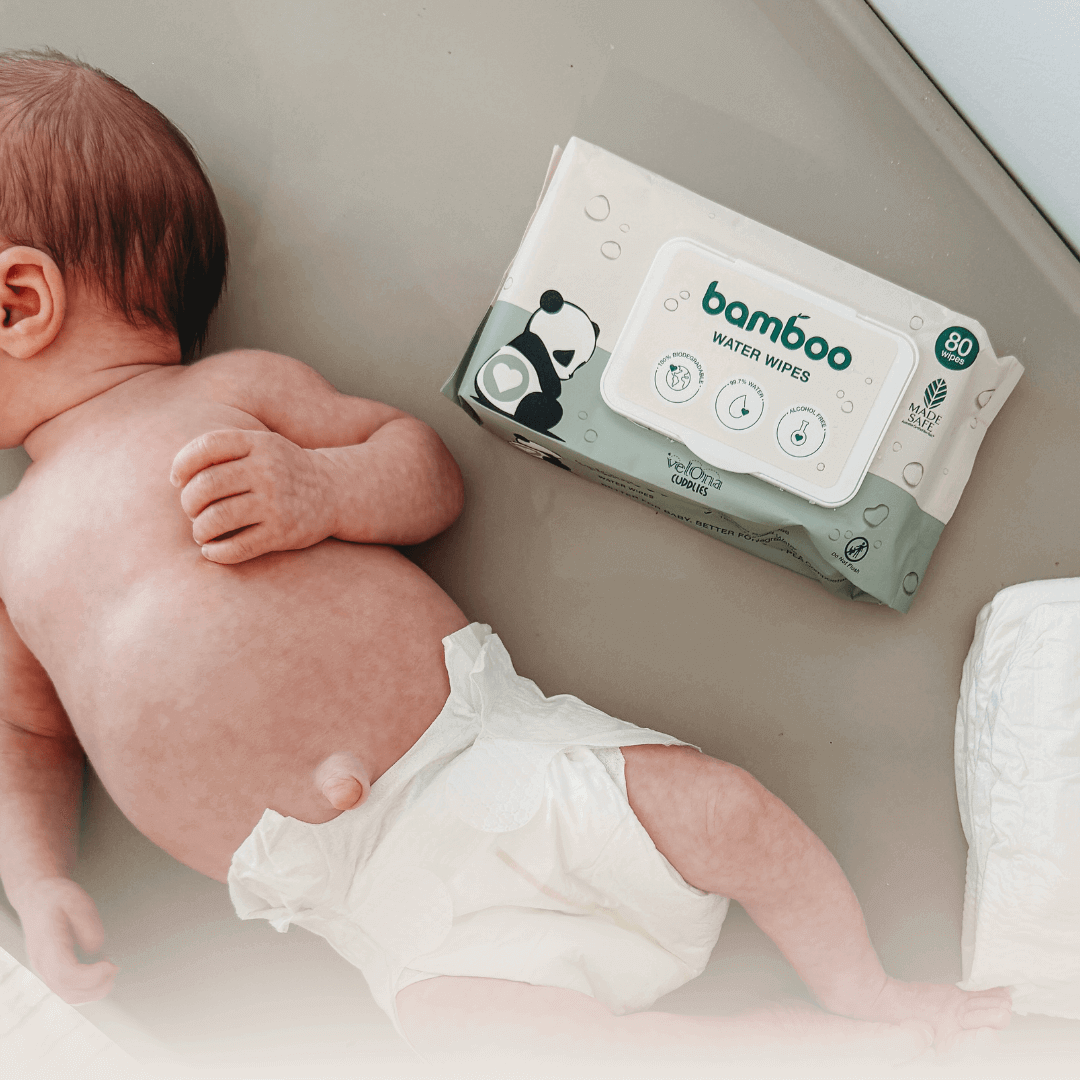 Newborn baby lying on a soft surface wearing a nappy, with a pack of baby water wipes placed beside them - ideal for illustrating gentle, safe options for newborn skincare.