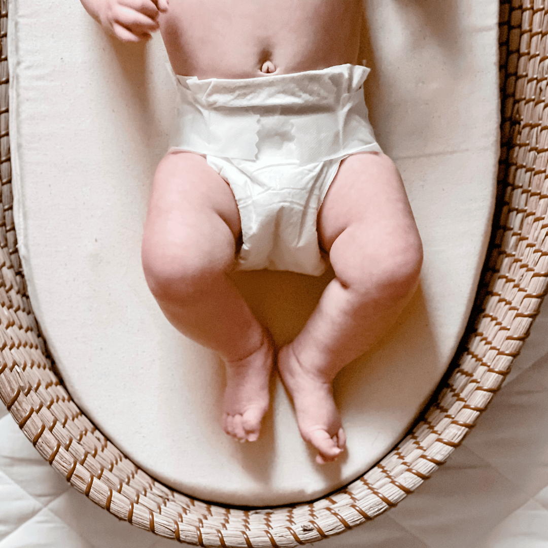 Baby wearing a Cuddlies nappy lying in a bassinet