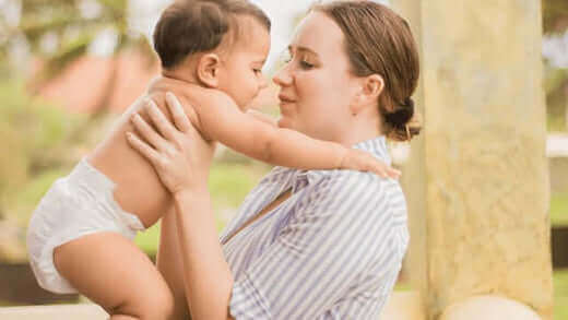 Mum and baby smiling and hugging in a Cuddlies nappy – safe, soft, and eco-friendly baby care moments
