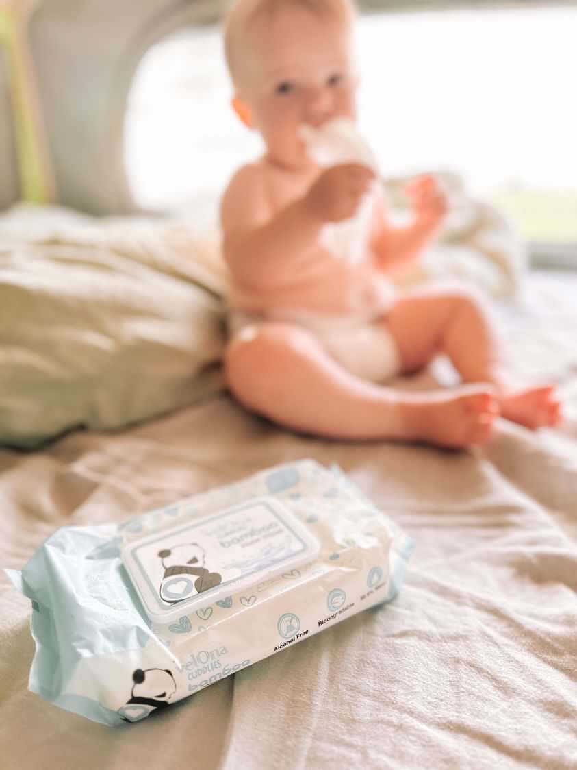 Cuddlies water wipes and baby on bed