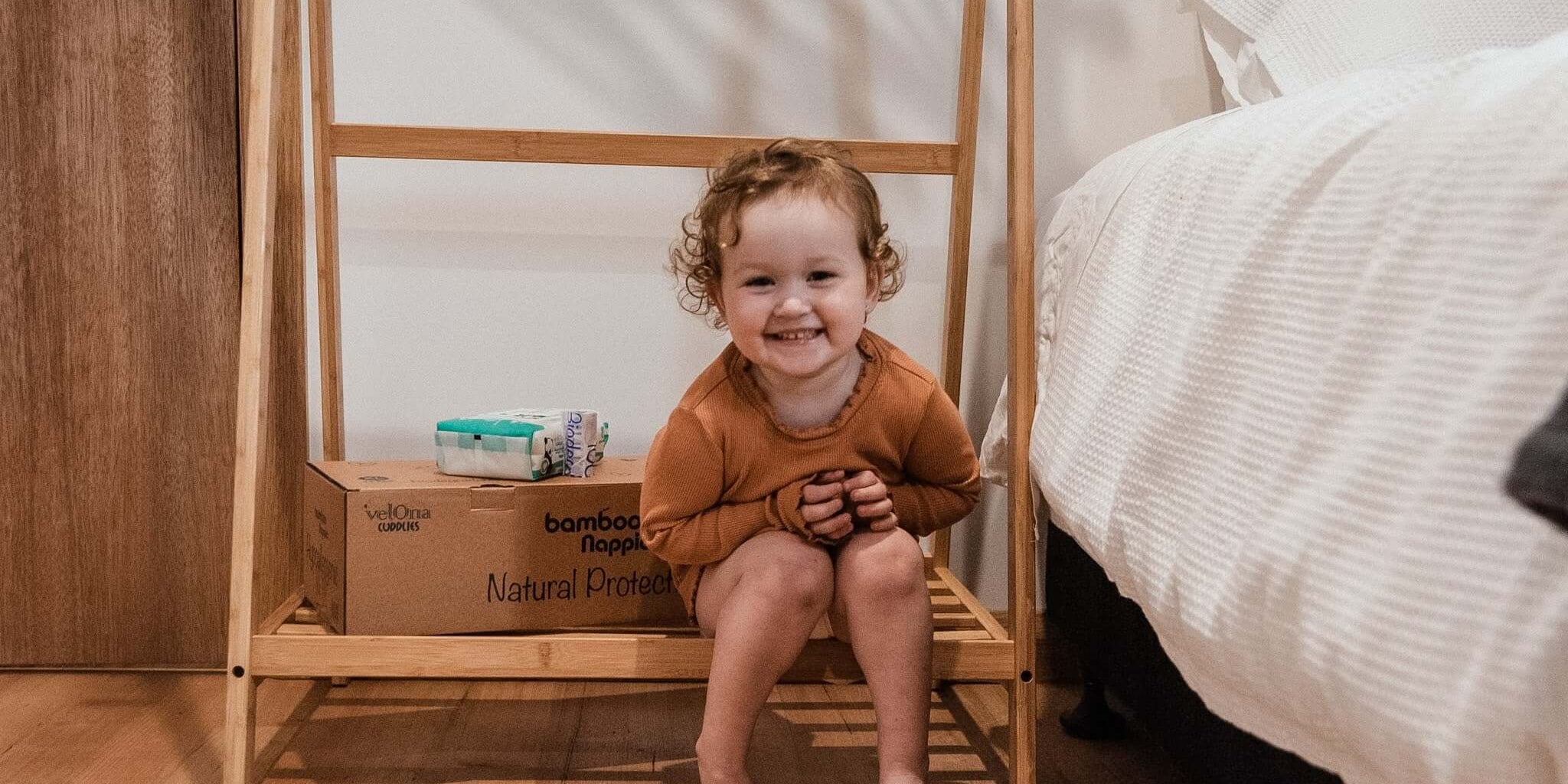 Baby sitting next to a Cuddlies nappy box and wipes