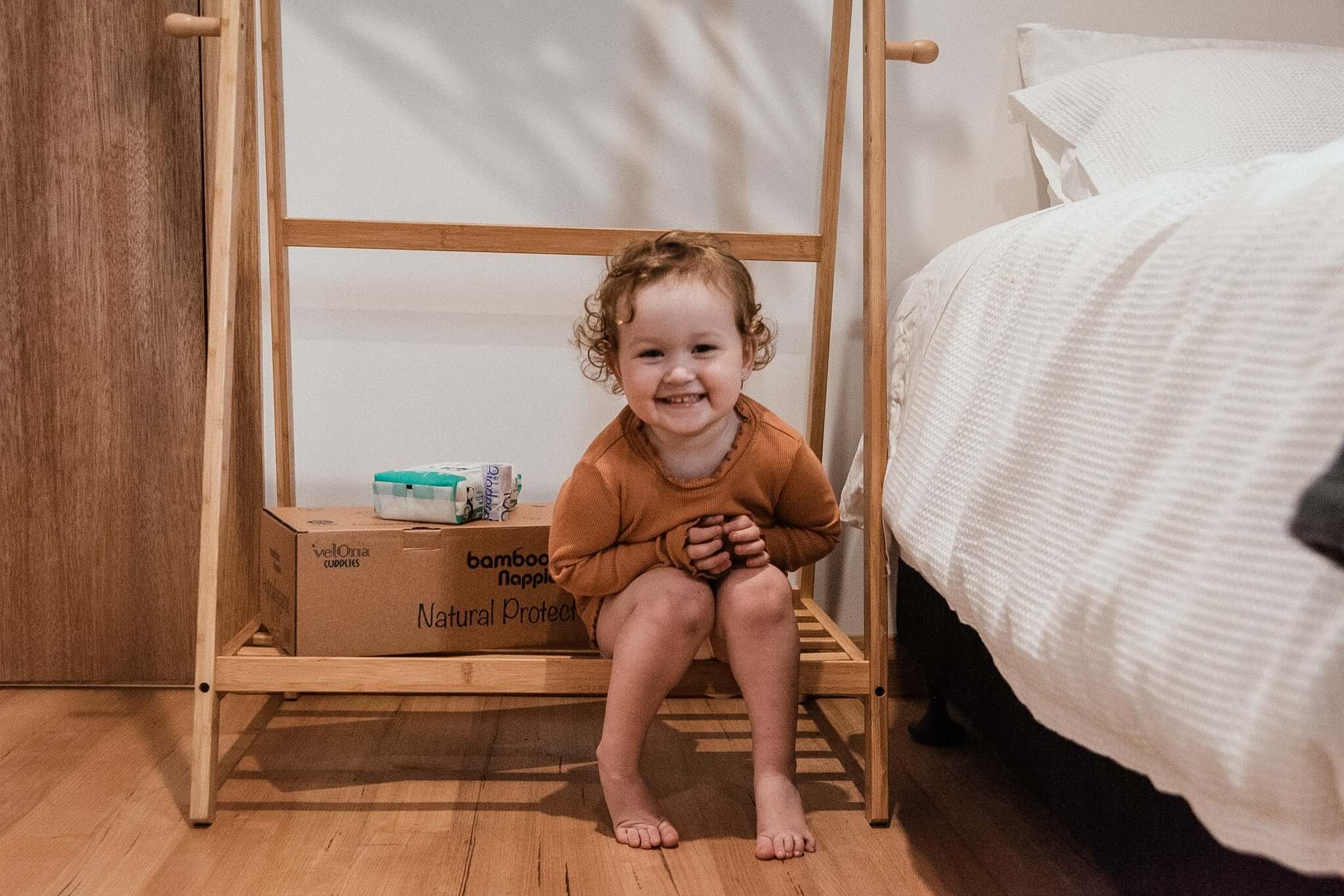 Baby sitting next to a Cuddlies nappy box and wipes